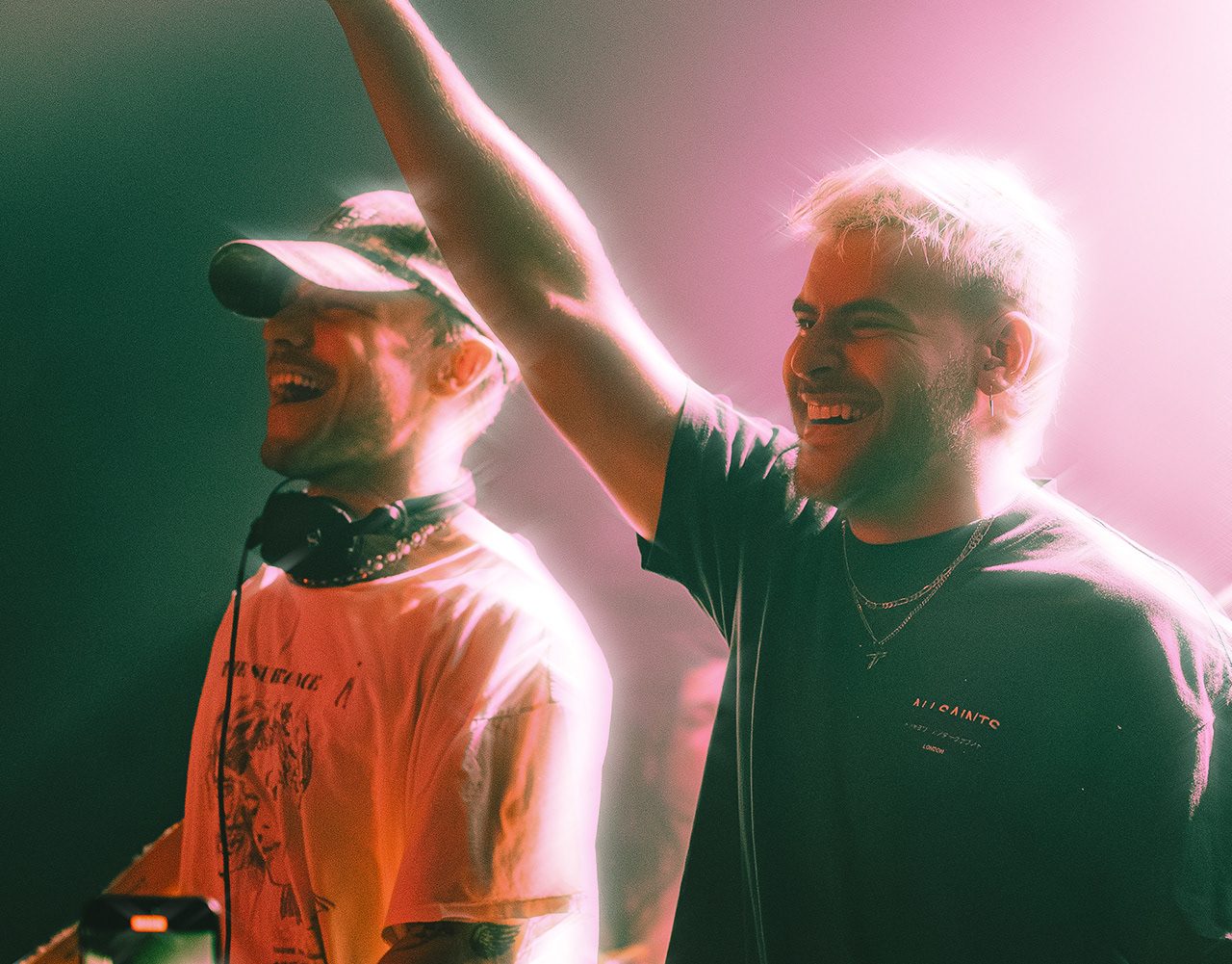 SIDEPIECE celebrating behind the decks under pink stage light